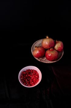 Pomegranate close-up with seeds in bowl close-up, Black background, macro photography