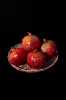 Pomegranates on wooden plate, Black background, macro photography