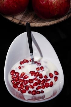 Bowl of pomegranate seeds with yogurt, macro photography