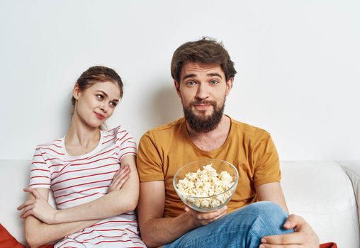 Man and woman on the couch with popcorn watching TV shows. High quality photo