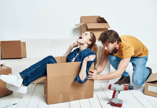 Man and woman boxes with things white sofa interior moving room. High quality photo