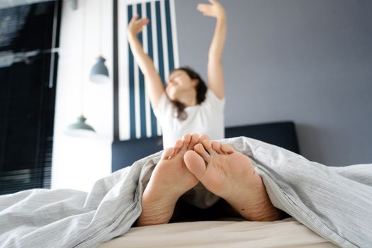 Beautiful girl wakes up in a good mood in a stylish apartment. View from the feet.