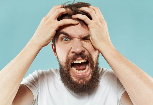 Model bearded man in white T-shirt on blue background irritability emotions model. High quality photo