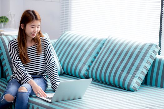 Beautiful of portrait young asian woman using laptop for leisure on sofa in living room, girl working online with notebook freelance with a happy, communication business concept.