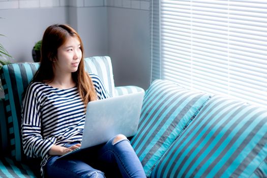 Beautiful of portrait young asian woman using laptop for leisure on sofa in living room, girl working online with notebook freelance with a happy, communication business concept.