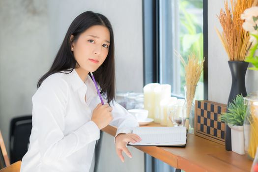 Beautiful asian young woman working online with laptop and think project for idea at modern cafe shop, business and freelance concept.