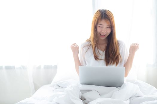 Beautiful happiness young asian woman using laptop work with success on bed in the home, girl and notebook shopping online with glad, communication concept.