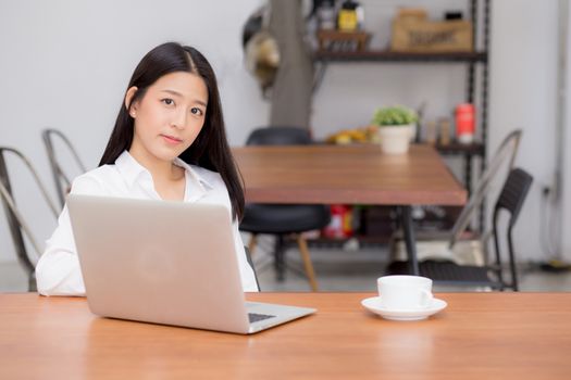Beautiful asian young woman working online on laptop sitting at coffee shop, professional female freelancer using notebook computer with connect to internet for distance job.