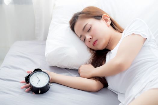 Beautiful asian young woman turn off alarm clock in good morning, wake up for sleep, girl holding alarm clock, time and lifestyle concept.