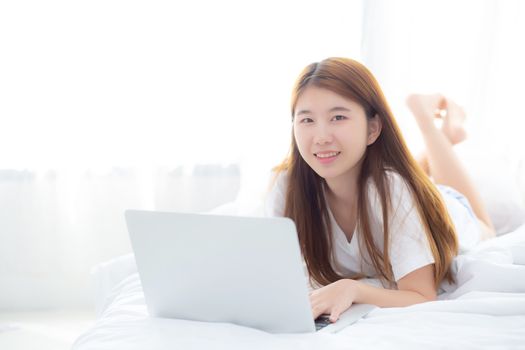 Beautiful asian young woman lying on bed using laptop at bedroom for leisure and relax, freelance with girl working notebook, communication concept.