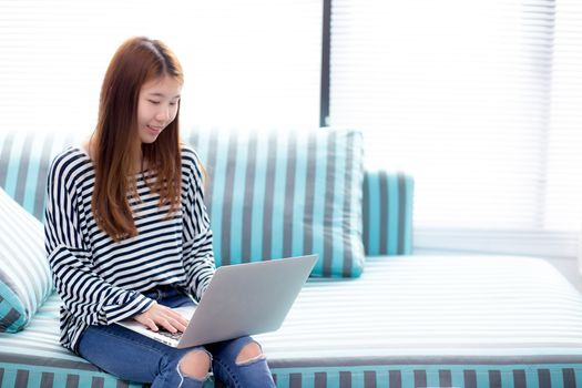 Beautiful of portrait young asian woman using laptop for leisure on sofa in living room, girl working online with notebook freelance with a happy, communication business concept.