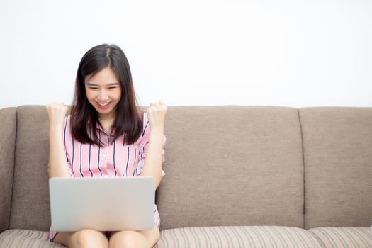Beautiful of portrait asian young woman excited and glad of success with laptop on sofa, girl working living room at home, career freelance business concept.