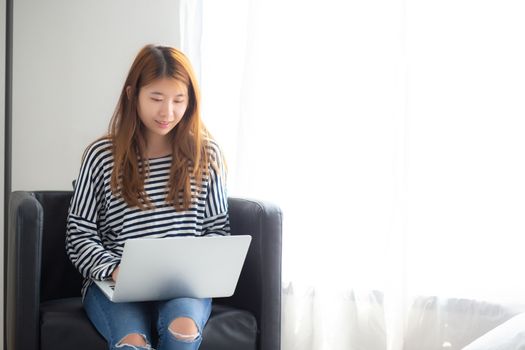 Beautiful of portrait young asian woman using laptop computer  for leisure on chair at living room, girl working online with notebook freelance, communication business concept.