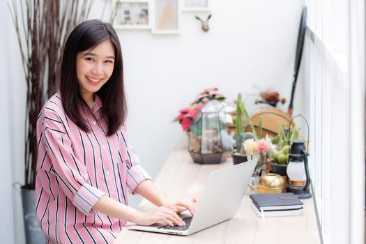 Beautiful of portrait asian young woman working online on laptop sitting at coffee shop, professional female freelancer using notebook computer with connect to internet for distance job.