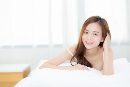 Beautiful portrait young asian woman lying and smile while wake up with sunrise at morning, lifestyle and relax concept.