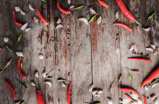 Fresh red chili and garlic with pepper seeds on wooden background