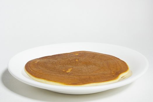 Freshly baked pancake on a plate on a white background