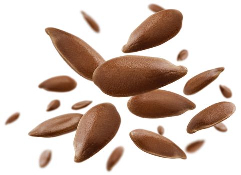 Flax seeds are levitated on a white background.