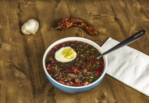 Cold vegetable soup with egg on a wooden table