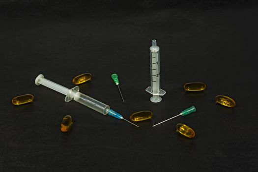 On a black background, there are syringes with needles and medical preparations