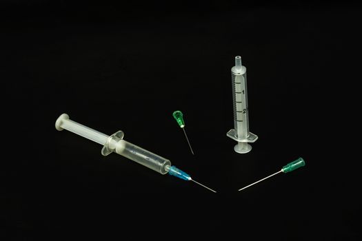 Medical syringe and needles on a black background