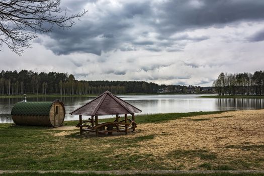 Bathhouse and gazebo on the shore near the forest lake