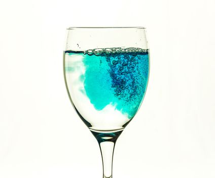 Blue liquid fills glass glass with transparent water