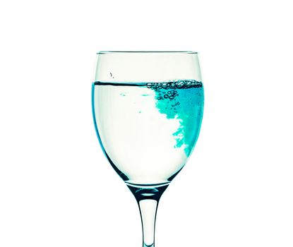 Blue liquid fills a glass with transparent water