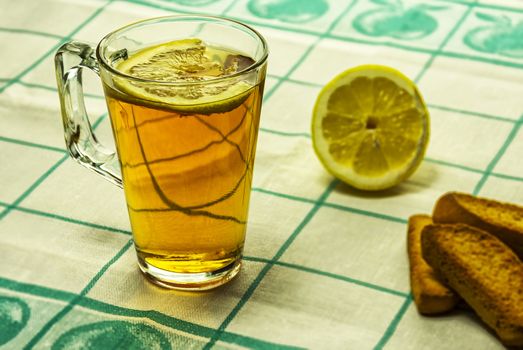 On the table is a glass of tea with lemon and lie vanilla biscuits