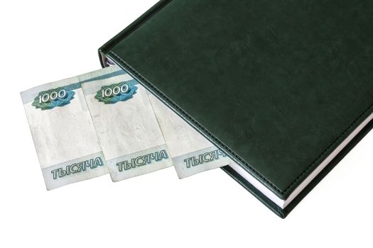 Between the sheets of the closed diary, one can see a part of the denominations of 1000 Russian rubles