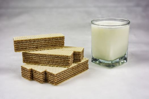 A glass of yogurt and wafers with chocolate filling on a gray background