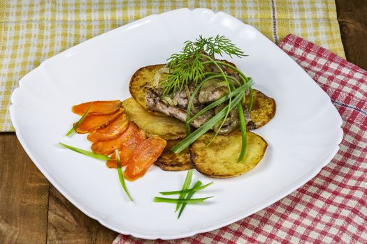 Hot dishes. Fried potatoes with pieces of fried meat on a white plate