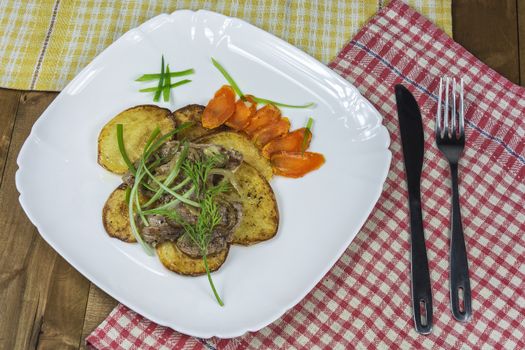 On slices of fried potatoes lie pieces of fried meat