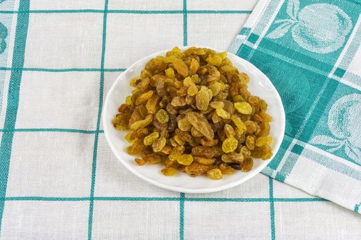 White saucer with raisins on a cloth tablecloth