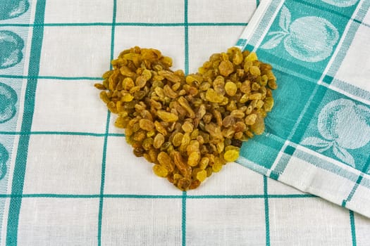 On a tissue napkin is a raisin laid out in the form of a heart