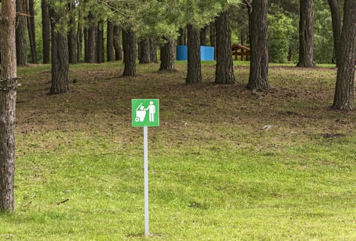 The plate with the inscription "Do not litter" is installed in the forest in the recreation area