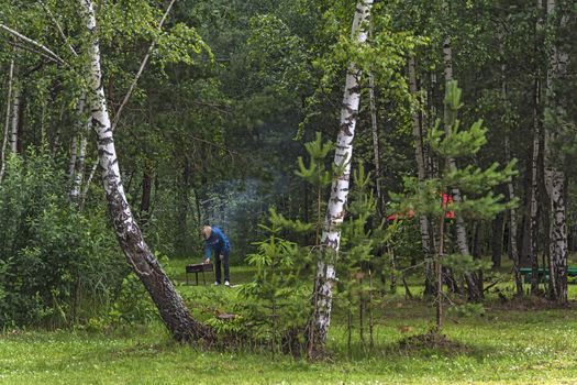 Summer vacation in the forest. The man is frying shish kebab on the grill