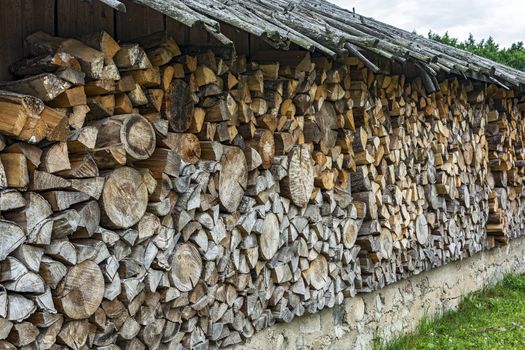 Under a canopy stacked firewood in a woodpile for the winter season