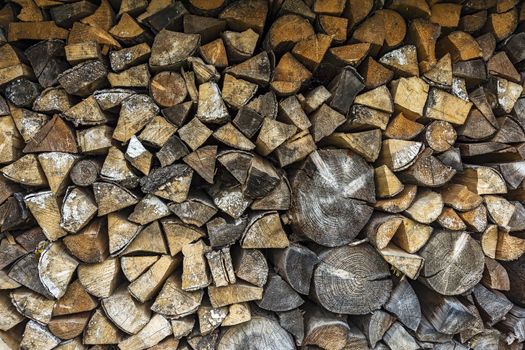 The firewood is packed in a woodpile for the winter season