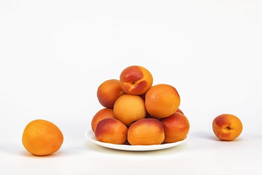 Fresh ripe apricots on a white saucer on a white background