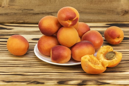 Ripe fresh apricots lie on a wooden table and on a white saucer