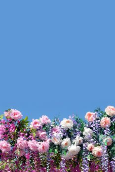 Decoration from many spring flowers at the bottom part on the image isolated on blue background on sunny day