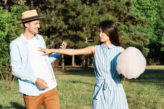Asian woman and guy in the park with cotton candy in hand