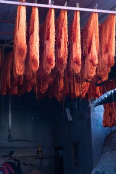 Dyed wool hanging to dry in souk in Marrakech Morocco Marrakechs Sebbaghine vibrant Dyers Souk. Skeins of red, blue, yellow, gold hanging from the ceiling with beautiful light shafting making a magical scene of ancient berber traditions High quality photo