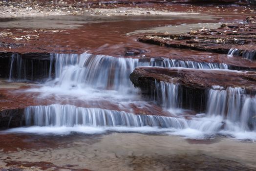 Beautiful waterfall streaming over red colored bedrock in the Left Fork North Creek, Zion National Park.