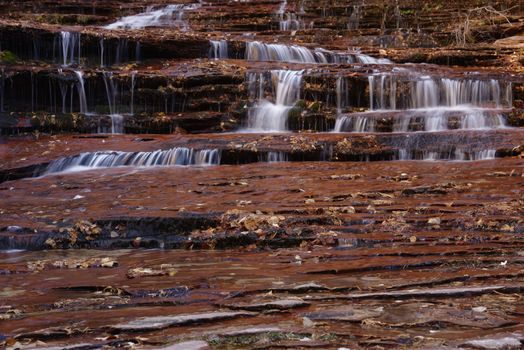 Beautiful waterfall streaming over red colored bedrock in the Left Fork North Creek, Zion National Park.