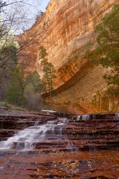 Beautiful waterfall streaming over red colored bedrock in the Left Fork North Creek, Zion National Park.