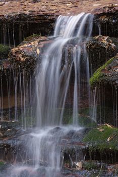 Beautiful waterfall streaming over red colored bedrock in the Left Fork North Creek, Zion National Park.