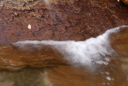 Beautiful waterfall streaming over red colored bedrock in the Left Fork North Creek, Zion National Park.