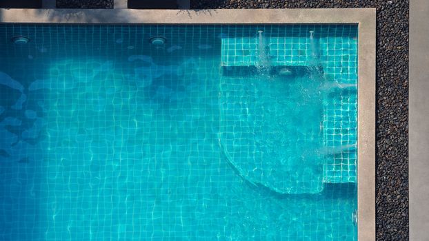 Water streaming corner in swimming pool top view and people enjoyed together on summer vacation day.